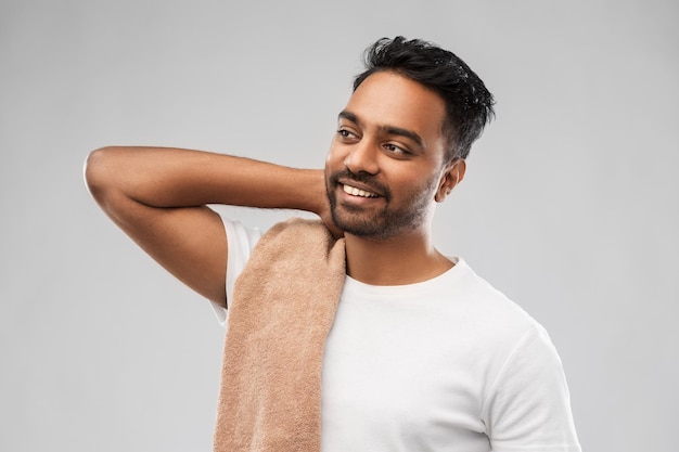 smiling indian man with towel over grey background