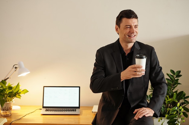 Uomo d'affari ispirato sorridente con la tazza di caffè