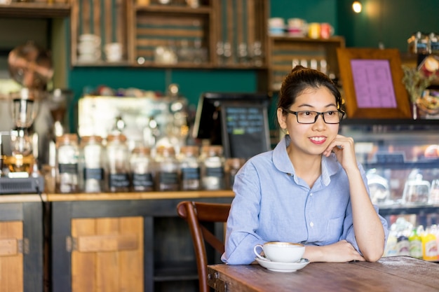 Smiling intelligent girl waiting for order in cafe.