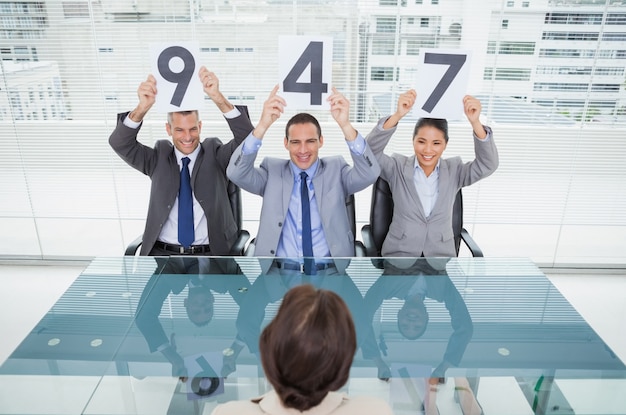 Smiling interview panel holding signs above their head giving marks to their applicant