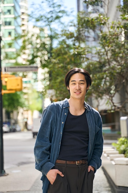 smiling Japanese man holding hands in pockets wearing stylish casual outfit looking at camera