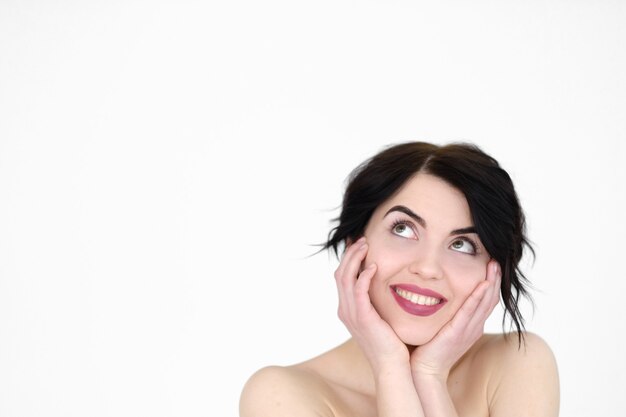 smiling joyful woman holding head in hands on white wall.