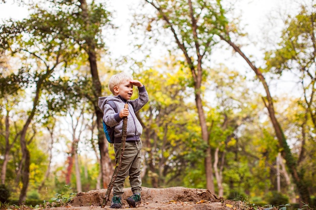 Smiling kid during autumn adventure in park in sunny day.