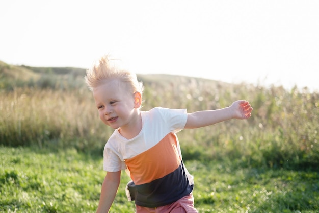 Smiling kid blond boy with in nature in a windy and sunny day