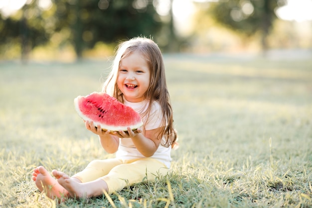 Smiling kid girl eating ripe watermelon