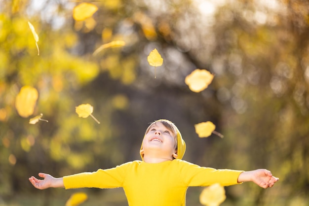 Улыбающийся ребенок веселится на свежем воздухе осенью