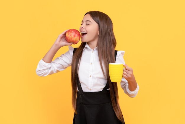 Smiling kid keep water balance in body teen girl with apple fruit and tea cup be hydrated