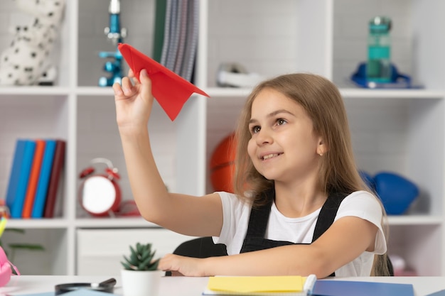 Smiling kid play with paper plane in school classroom