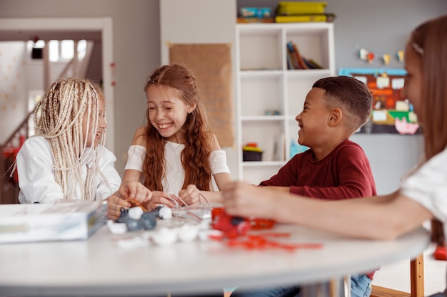 学校の机でDIYの建設を作成する笑顔の子供たち