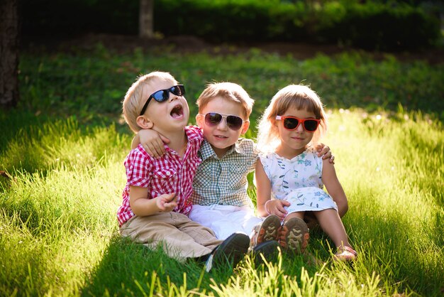 Bambini sorridenti in giardino in occhiali da sole