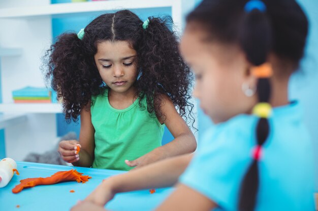 Smiling kids using modelling clay at their desk