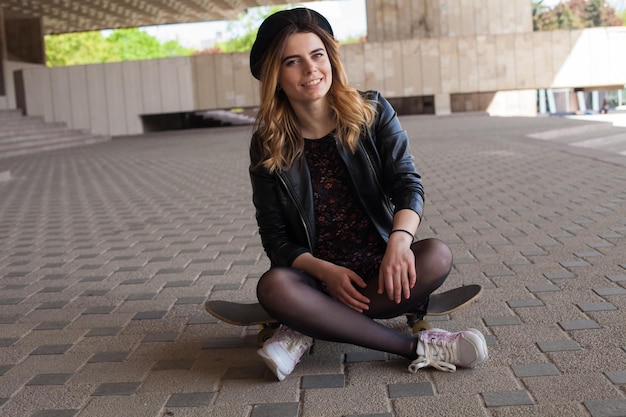 Smiling lady sitting on the skateboard