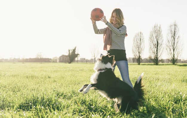 彼女の犬と自由な時間を取って笑顔の女性