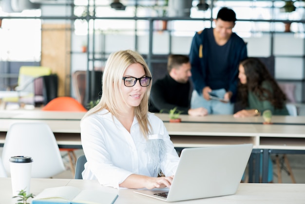 Smiling lady typing on laptop in office