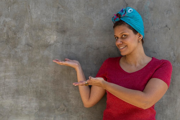 Smiling Latin  afro woman with scarf on her head points with her both bad guys to empty space