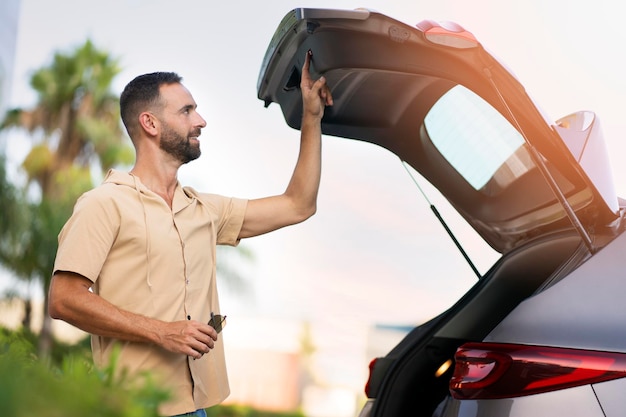 Smiling latin driver opening car trunk planning road trip. man\
choosing new car. transportation