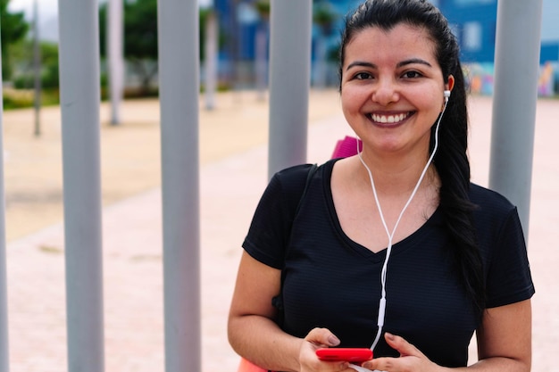 그녀의 휴대 전화에 메시지를 보내는 웃는 라틴 여자