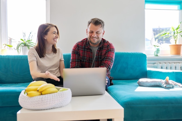 Smiling laughing positive couple 40 years old husband and wife looking at laptop