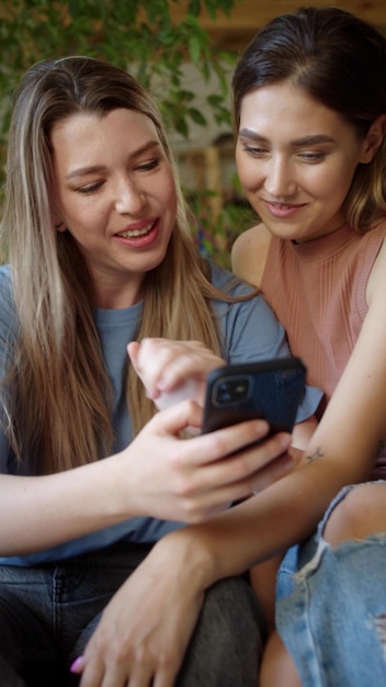 Photo smiling lesbian couple looking at mobile at home
