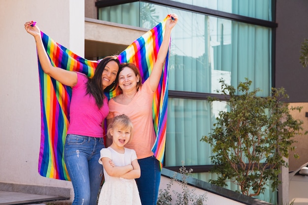 그들의 입양 딸과 함께 웃는 레즈비언 커플. lgbt 깃발을 든 게이 가족