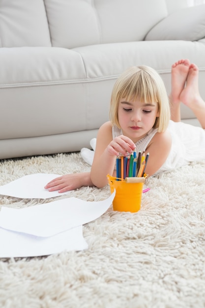 Smiling litlle girl drawing lying on the floor