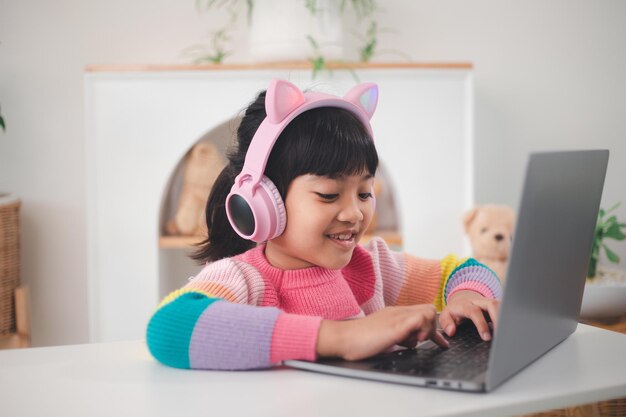 Smiling little Asian girl have a video call distant class with teacher using laptop, social distance during quarantine isolation during the Coronavirus