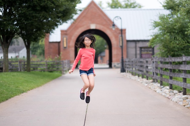 Smiling little Asian girl jump up in the park