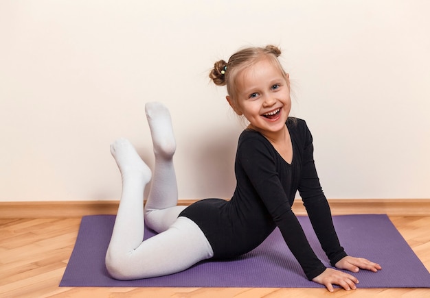 Smiling little ballerina training at home on the floor