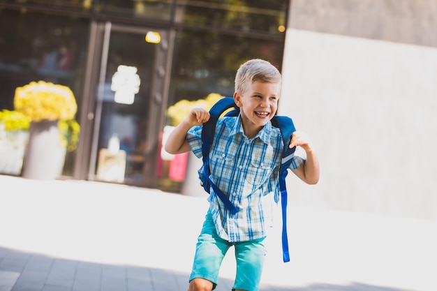 Photo smiling little boy in blue shorts and shirt walking to school happy and smiling boy on his first day at school