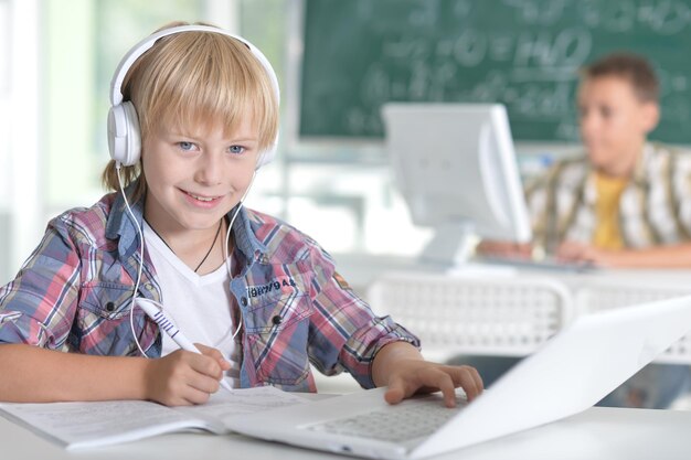 Smiling little boy in the classroom, his classmate on background