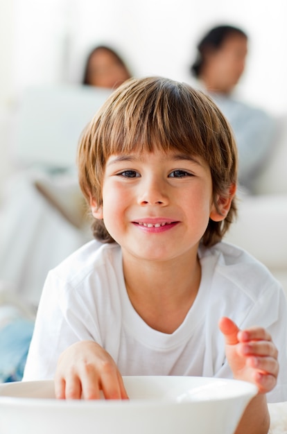 床に横たわるチップを食べる小さな男の子を笑って