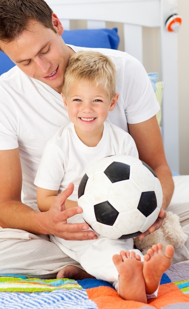 Smiling little boy and his father playing with a soccer ball