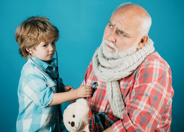 Smiling little boy playing doctor and listening old grandfather with stethoscope little doctor boy i