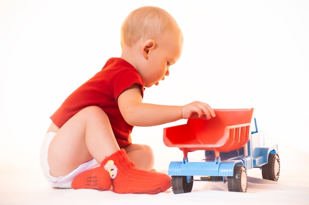 笑顔の小さな男の子がおもちゃの車で遊ぶ