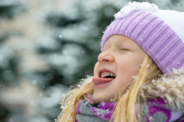 Smiling little girl catching a snowflakes with her tongue