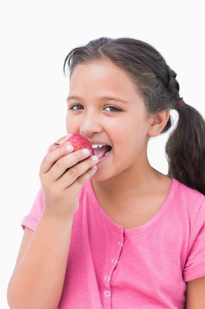 Smiling little girl eating apple