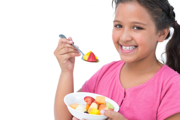 Smiling little girl eating fruit salad