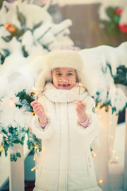 A smiling little girl at the fair lights sparklers and rejoices