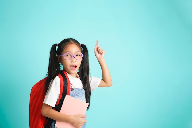 Smiling little girl in glasses pointing finger upward