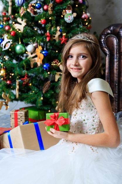 Smiling little girl holding a gift box in a New Year's interior