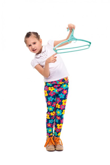 Smiling little girl holding a shirt in hanger. Cut out