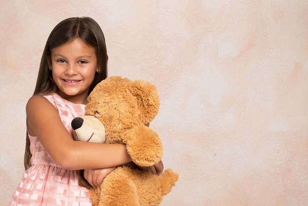 Smiling little girl holding a teddy bear. Copy-space on the right