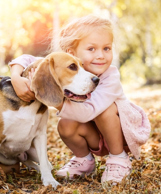 Smiling little girl hugging a beagle dog