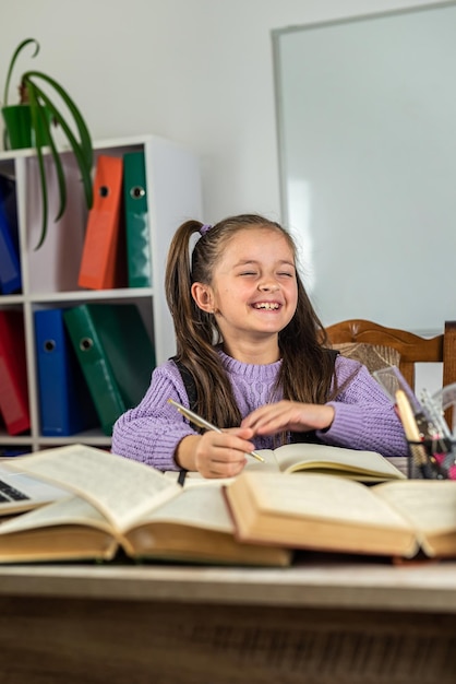 Smiling little girl is watching a video lesson on the computer