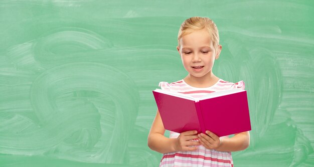 smiling little girl reading book at school