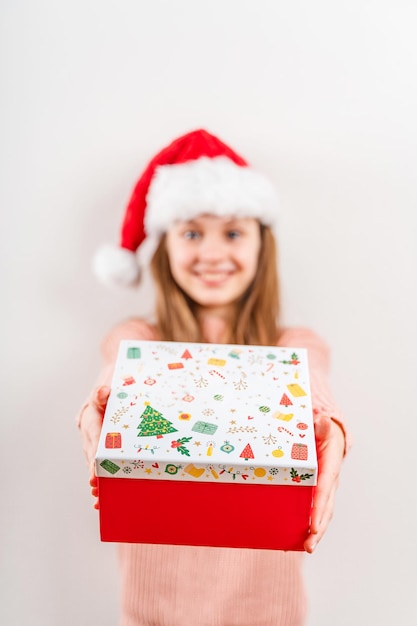 A smiling little girl in a red Christmas hat holds a New Years gift Holiday banner