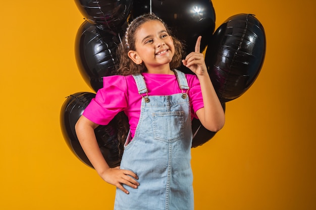 Smiling little girl with black balloons on black friday. low price festival