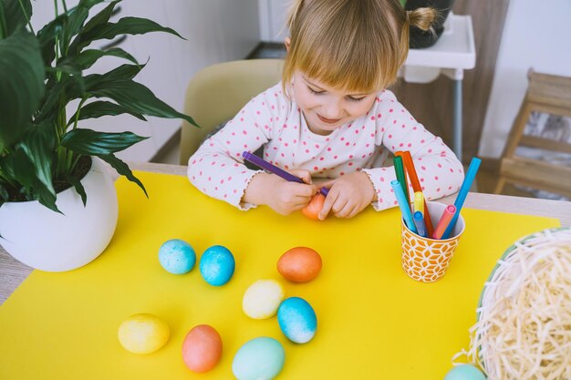 Smiling little girl with colorful eggs preparing for Easter Holiday Kids painting easter eggs