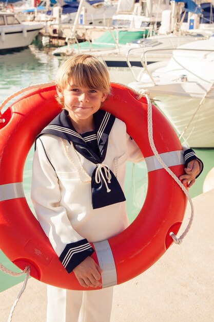 Smiling little sailor with ring buoy on harbor