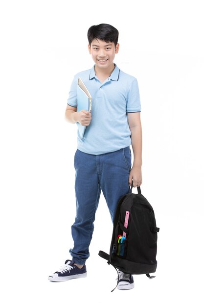 Smiling little student boy in blue polo t-shirt in with books and bag.